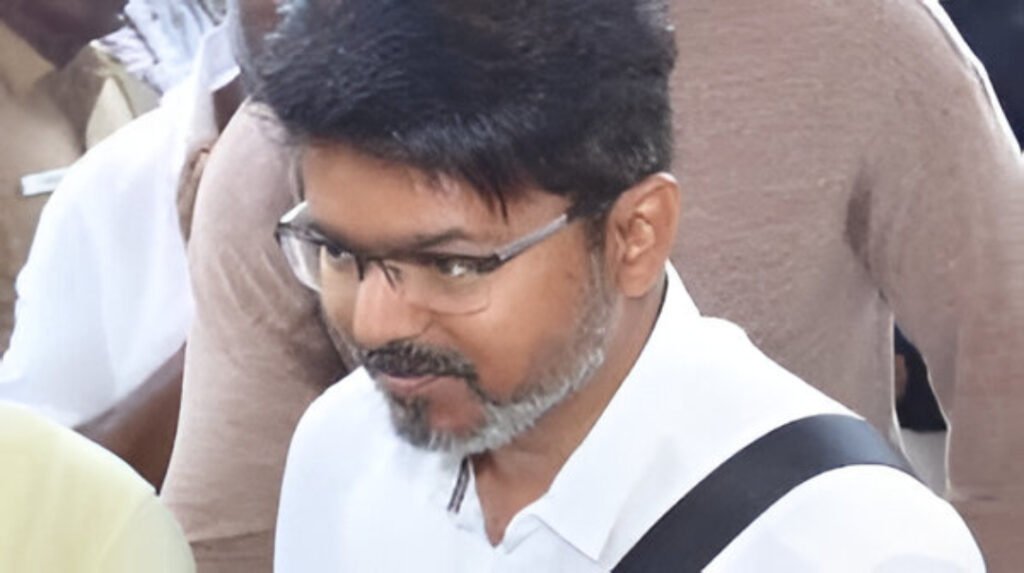 Vijay helped by security after tripping at Chennai airport amid a surge of fans.